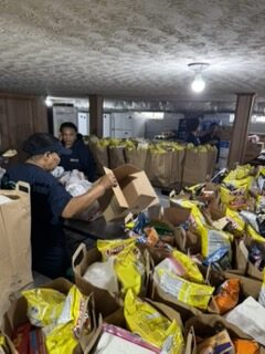group of people stand around a table of donated food